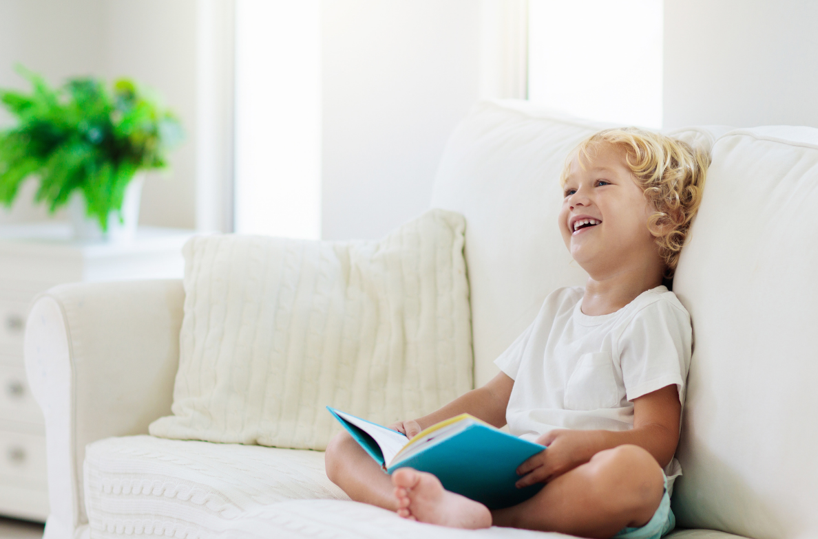 Toddler sitting and smiling holding a book
