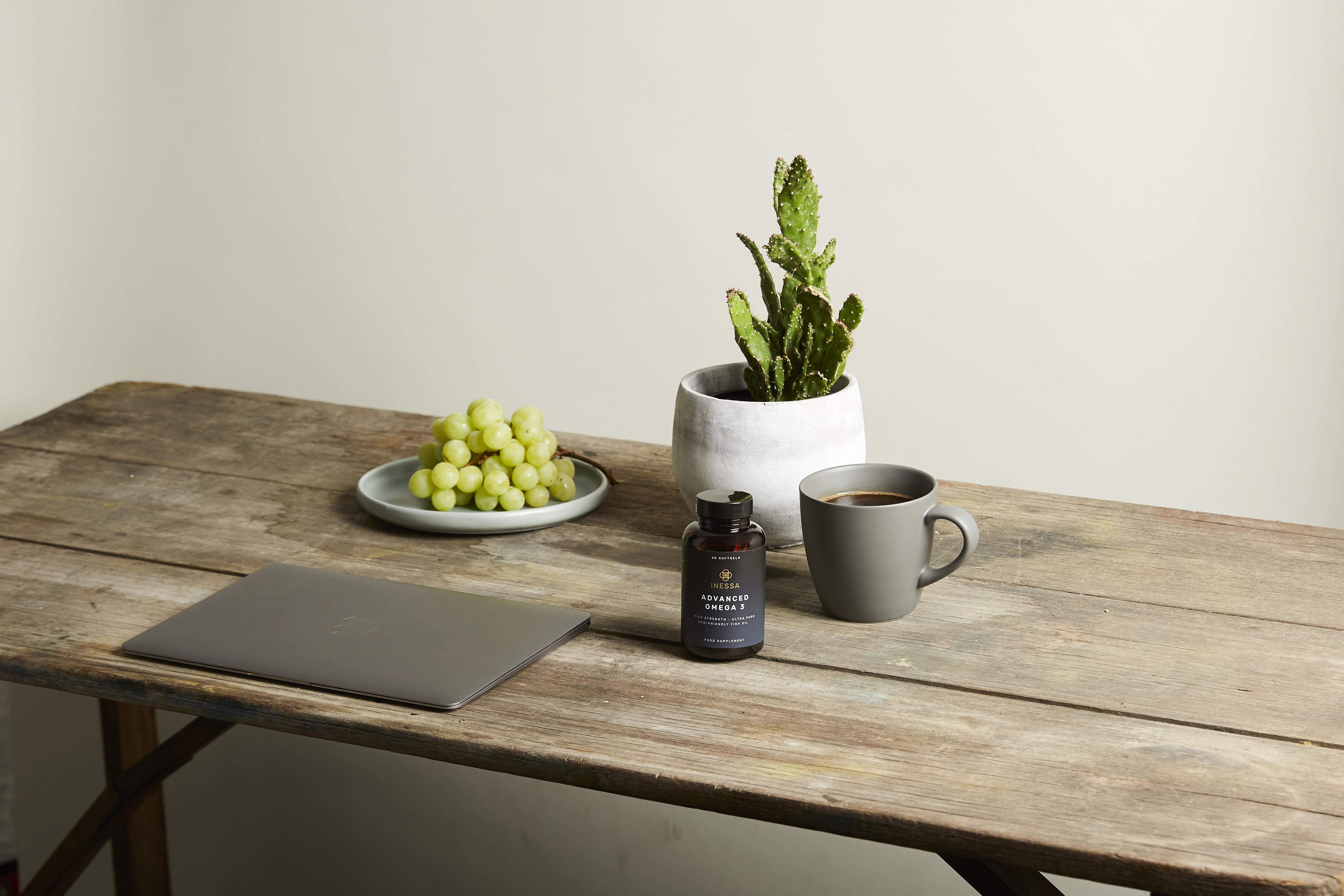 laptop, coffee, grapes and plant on desk