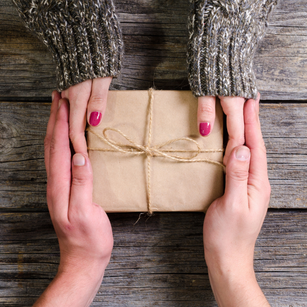 A wrapped present exchanging hands between two people