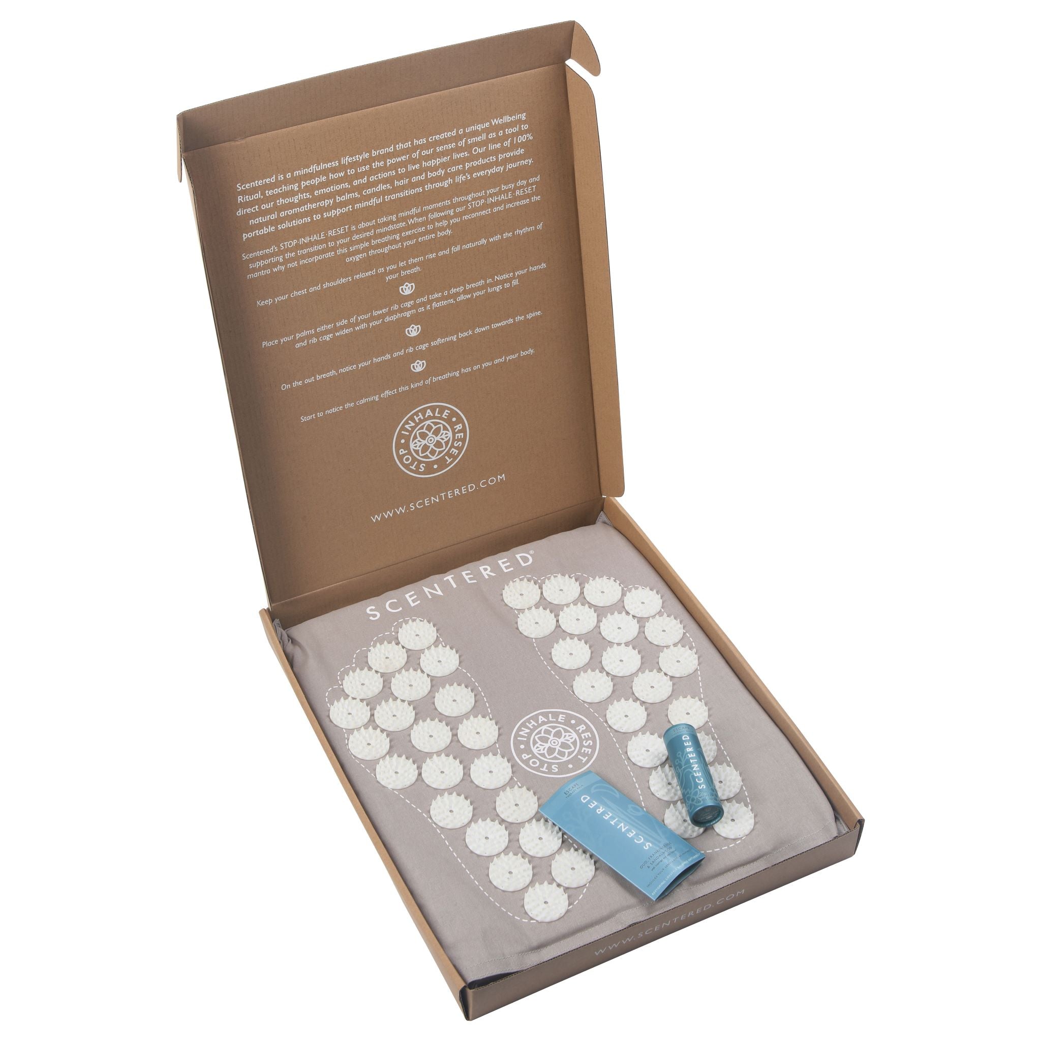 Scentered Acupressure Foot Mat in a cardboard box on a white back ground within the box contains a scentered escape balm included in the box