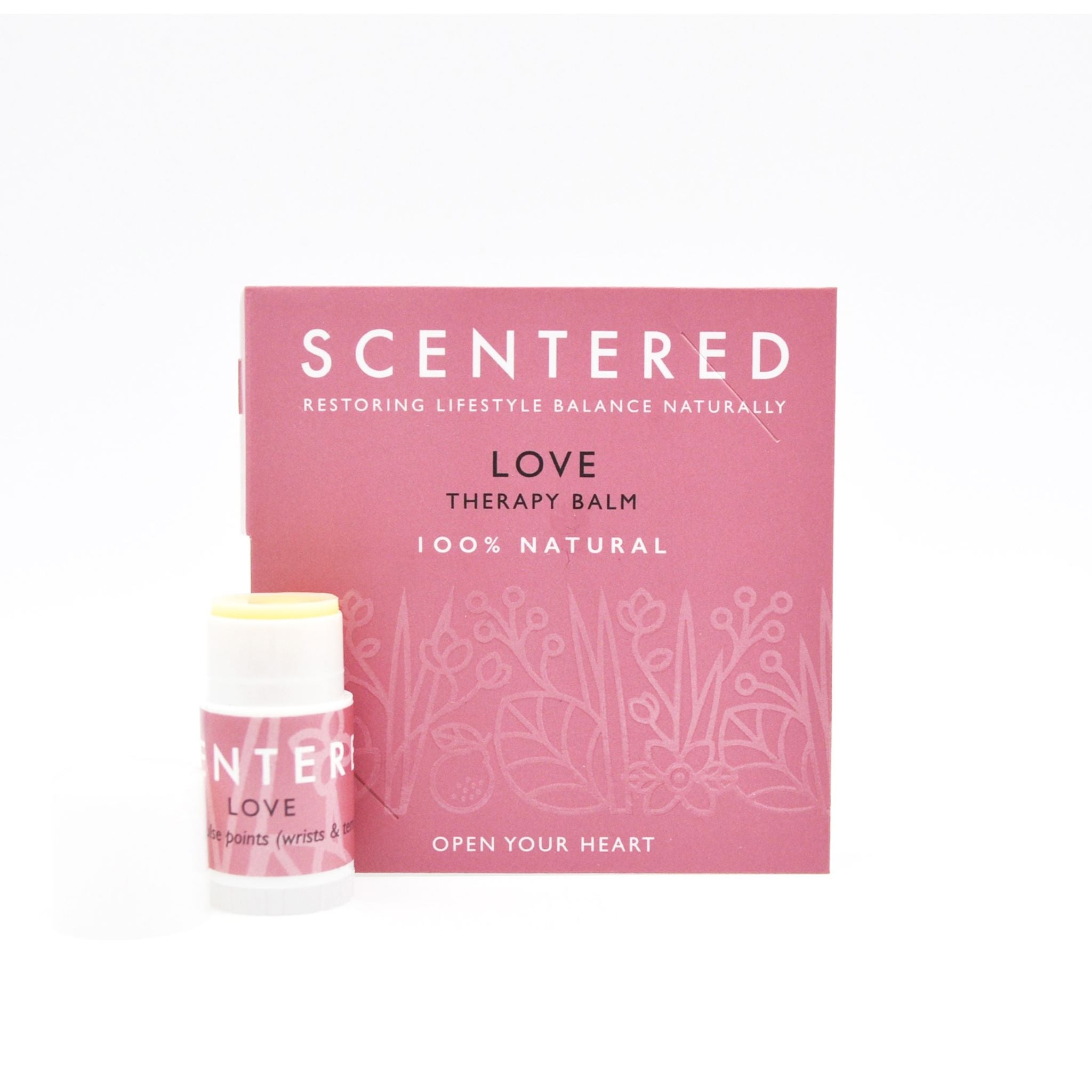 Scentered Love Mini Balm infront of Booklet with no cap and balm twisted up slightly.