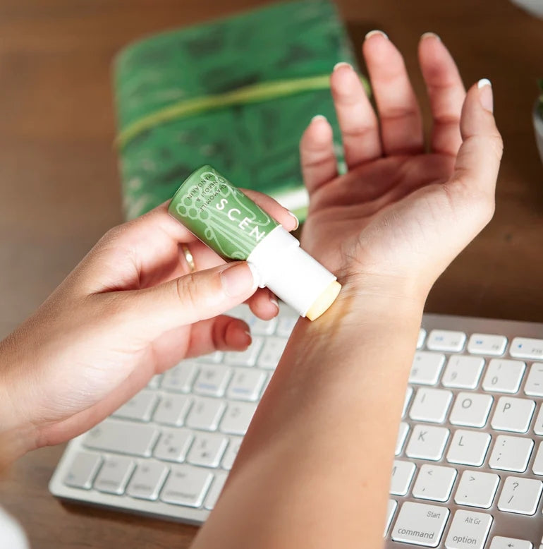 Scentered De-stress Calm Aromatherapy Balm being applied to pulse points at a laptop to help keep calm.