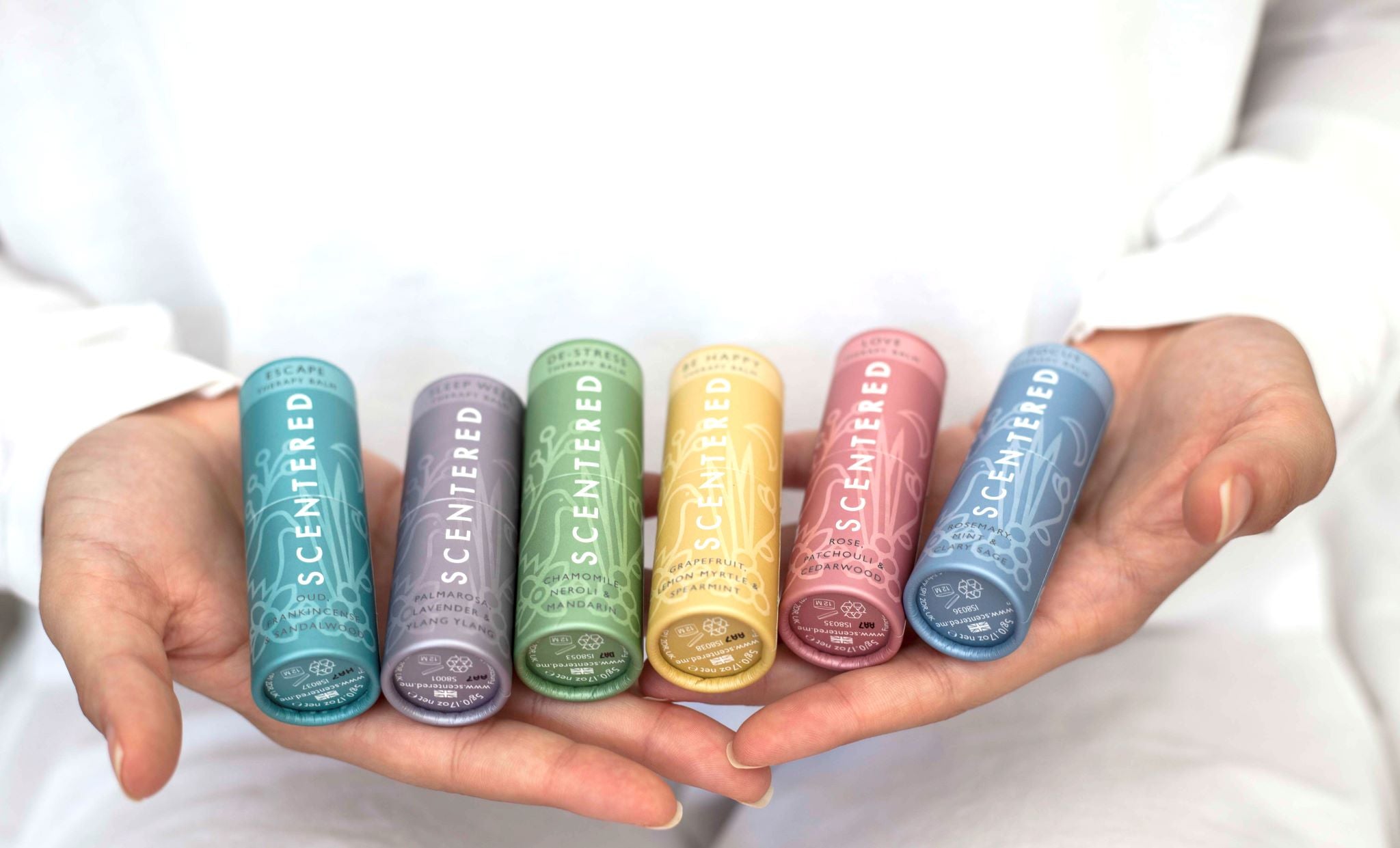 All of the six Scentered Aromatherapy Balms in a woman's hands, resigned to helping sleep, calming, relaxtion, happy