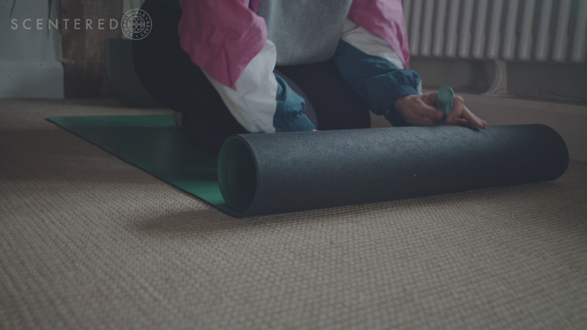 Video shows a girl dressed in relaxed clothing rolling out a yoga mat .  Then sitting on the yoga mat to apply the balm, she applies the Scentered Escape Relaxation balm to her wrist, stops for a moment to inhale the notes of the essential oils Oud, Frankincense and Cedar Wood and resets herself and the Scentered Escape Relaxation balm on the mat.   The Scentered logo including the words Scentered and Stop, Inhale, Reset; then appears to finish the video.