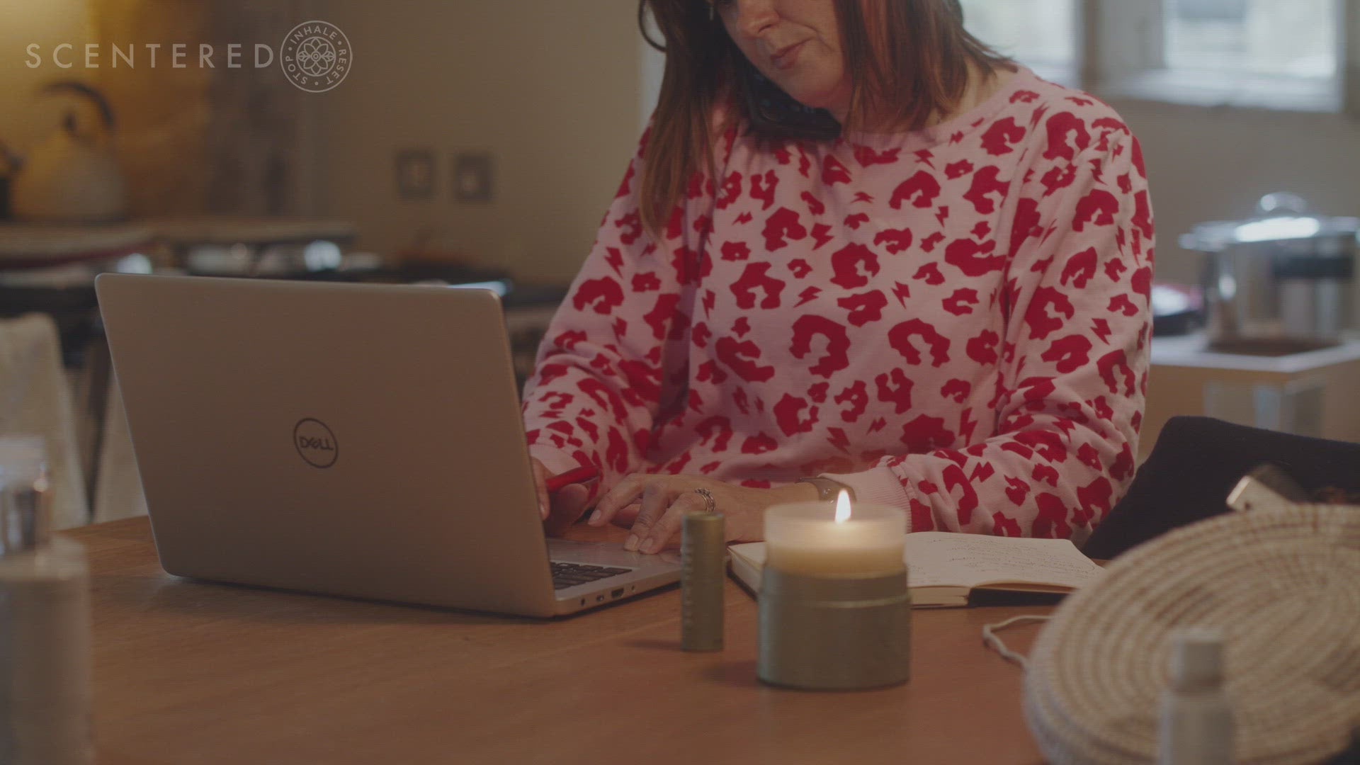Video showing a lady working at a lap top, writing then stops to apply the Scentered De-Stress Calm Aromatherapy Balm, she stops inhales the essential oils of Mandarin, Neroli and Camomile and resets and calmly places the balm down next to the glowing candle, paper and pen.   The Scentered logo including the words Scentered and Stop, Inhale, Reset; then appears to finish the video.